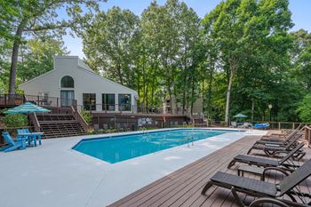 A pool with a deck and resident clubhouse in the background.